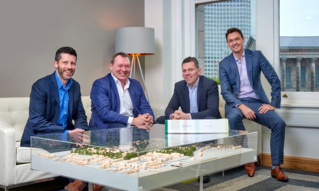 4 smiling men sitting around model of new development