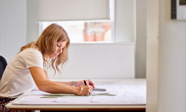 Charlotte Lewis Richborough Estates leaning on desk writing with drawings