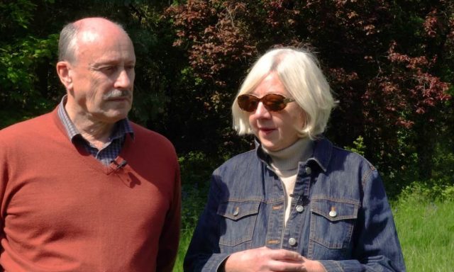 Photograph of the Deans Man and Woman standing next to each other outside surrounded by grass and trees in the sunshine
