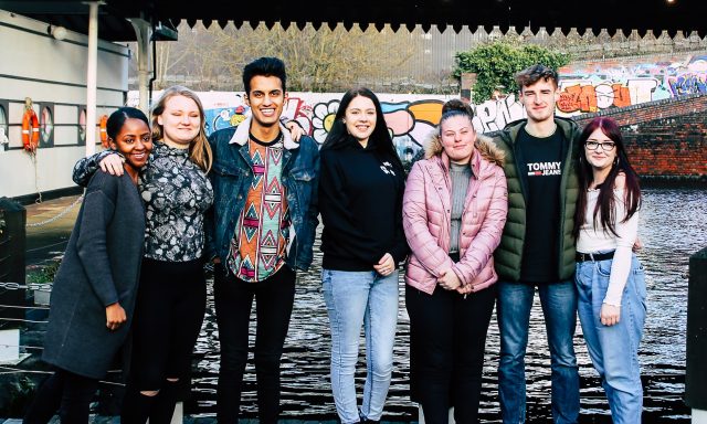 Image of young people standing outdoors with arms around eachother