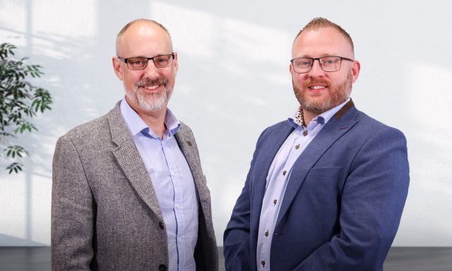 Two smiling men in office clothes celebrating their new appointment and promotion.